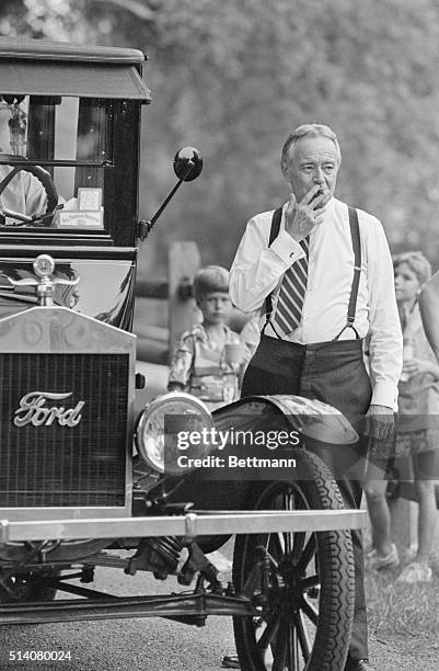 Jack Lemmon smokes a cigar, while standing next to a vintage car on the set of the mini-series, "The Ballad of Mary Phagan".