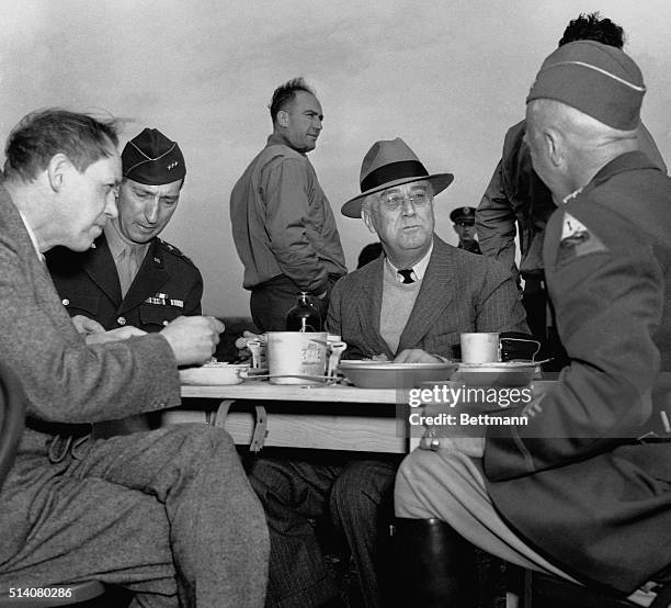 Presidential Adviser Harry Hopkins, General Mark Clark, U. S. President Franklin Delano Roosevelt, and General George S. Patton eat lunch from mess...