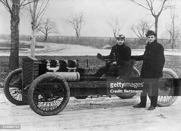 Henry Ford standing beside his famous racer 999 with Barney Oldfield at the tiller. Both Ford and Oldfield drove this four-cylinder, 80 horsepower...