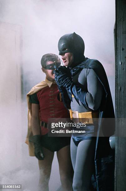 Adam West as Batman speaks into his phone while Burt Ward as Robin looks on in a scene from the television show, Batman.