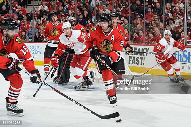 Andrew Ladd of the Chicago Blackhawks reaches for the puck in front of Duncan Keith as Tomas Jurco and Luke Glendening of the Detroit Red Wings watch...