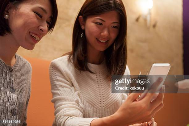 mujeres que están riendo para ver el teléfono inteligente - only japanese fotografías e imágenes de stock