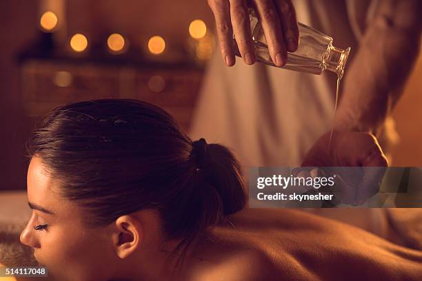 close-up of massage therapist pouring massage oil in hand. - massage oil stock pictures, royalty-free photos & images