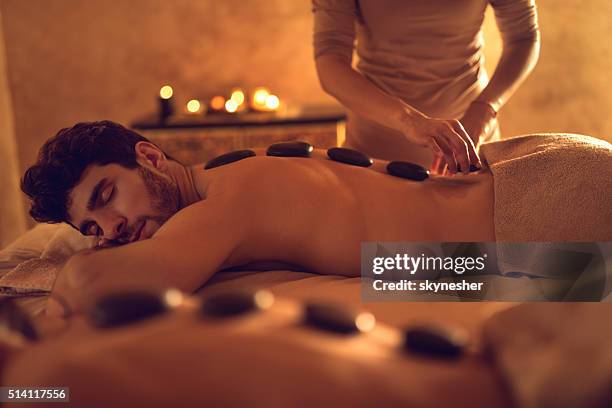 young man enjoying during hot stone therapy at the spa. - lastone terapi bildbanksfoton och bilder