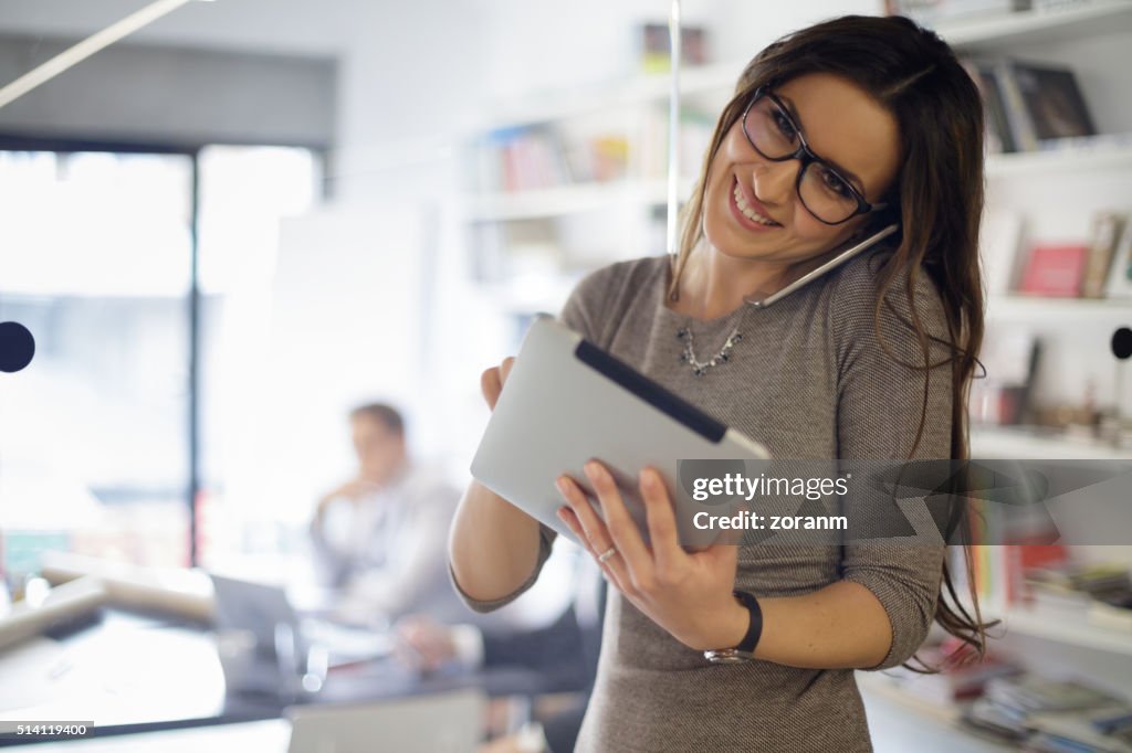 Mulher de Negócios fala no telefone e usa Tablet digital