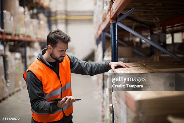 worker making a checklist in a warehouse with digital tablet - dockers stockfoto's en -beelden