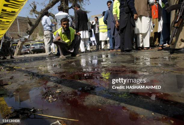 Pakistani security officials inspect the site of a suicide bombing in Shabqadar on March 7, 2016. - A suicide bomber killed 13 people and injured 23...