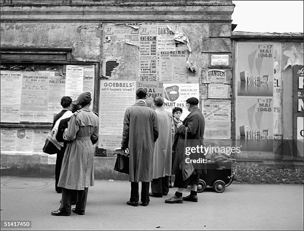 Group of Parisians look up at a French violent anti-zionist and anti-semitic placard is pasted up 13 May 1948 on a Paris wall comparing Israeli Jews...