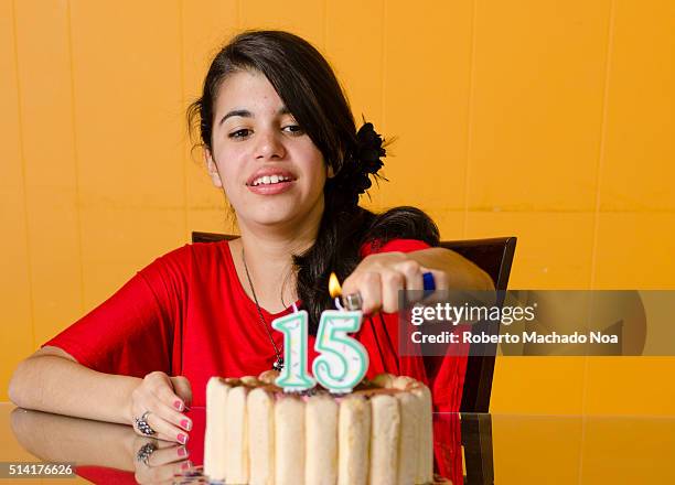 Quinces: Young Hispanic girl lighting 15 shaped candle on her birthday cake. Celebrating the 15th anniversary is an important tradition in Latin...