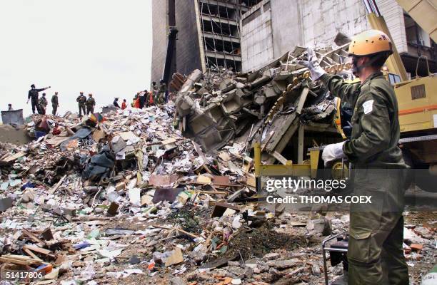 An Israeli rescue worker calls to colleagues 10 August as they stand on what remains of a building in front of the US embassy in Nairobi, four days...