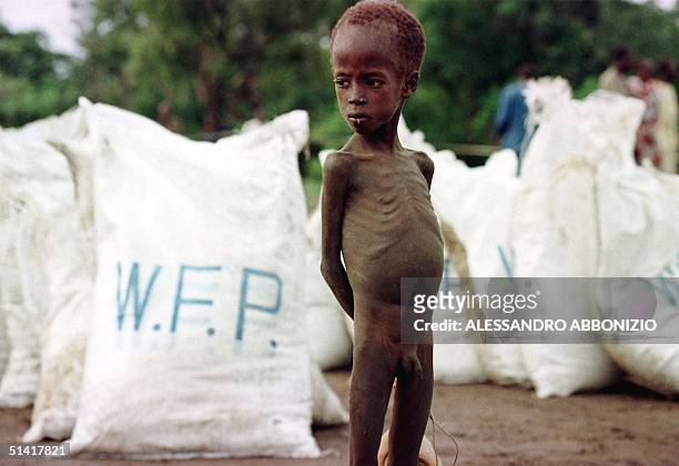 Young starving boy stands in front of relief food bags delivered by the World Food Programme 09 August after an airdrop by the WFP in the village of...