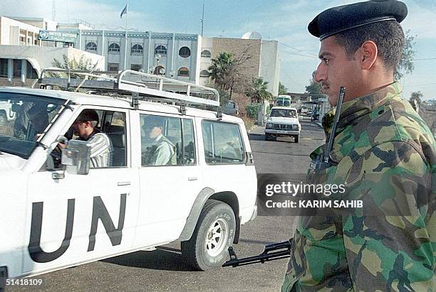An Iraqi soldier watches as members of the UN weapons inspections team in Baghdad leave headquarters for their daily work 10 December, one day after...