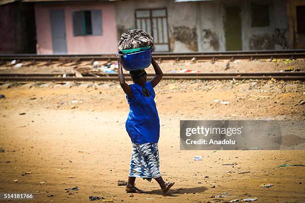 Guinean woman carries a bucket on her head as she walks in Conakry, Guinea on March 7, 2016. Guinean women give their children to foreigners who...