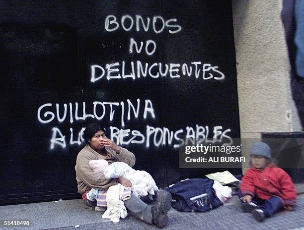 Woman an her children begg outside of Banco Rio, in the financial district of Buenos Aires, 18 June 2002. AFP PHOTO/Ali BURAFI Una mujer con sus dos...