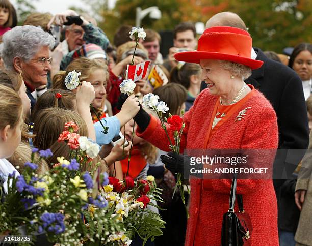 Queen Elizabeth II accepts flowers and a Canadian flag during a walk-about in Fredericton, New Brunswick, Canada, 11 October 2002, half way through...
