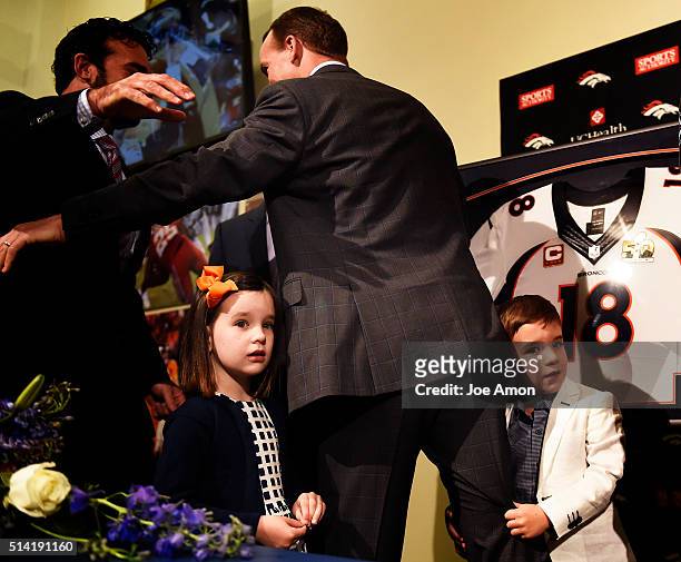 Denver Broncos quarterback Peyton Manning's 4 year old twins Mosley and Marshall hang onto daddy's leg after a press conference to announce his...