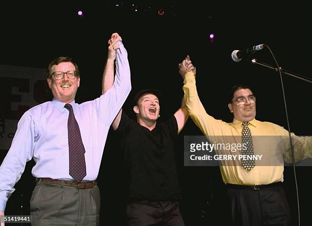 Irish rock band U2's lead singer Bono holds up the arms of Ulster Unionist leader David Trimble and SDLP leader John Hume on stage during a concert...