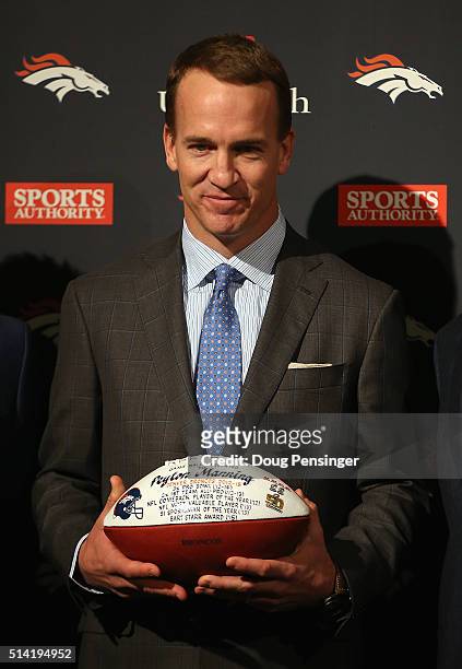 Quarterback Peyton Manning holds a game ball presented to him by the Denver Broncos after announcing his retirement from the NFL at the UCHealth...