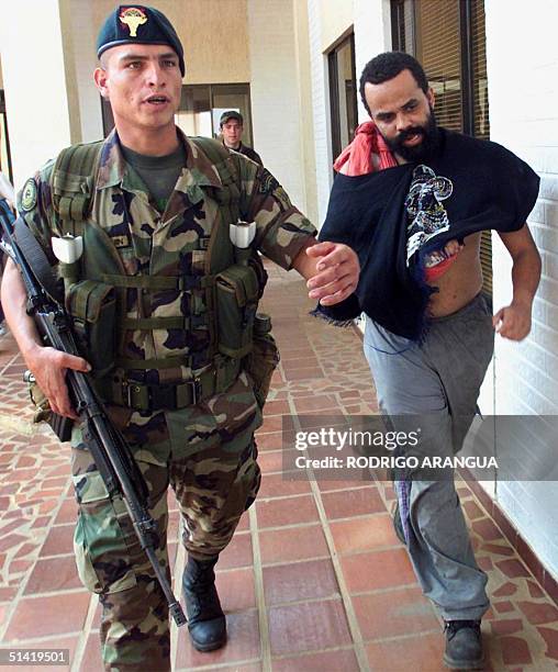 Brazilian drug kingpin Luiz Fernando da Costa is escorted by a soldier after being presented to the press 22 April 2001, at the Marandua de Bichada...