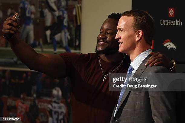 Quarterback Peyton Manning poses for a photograph with former teammate Kenny Anunike after announcing his retirement from the NFL at the UCHealth...