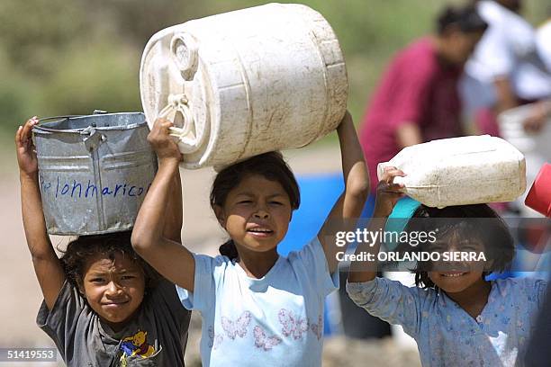 Three girls carry containers of water in Tegucipalpa, Honduras. Tres ninas recorren con recipientes largas distancia en Tegucipalpa, para conseguir...