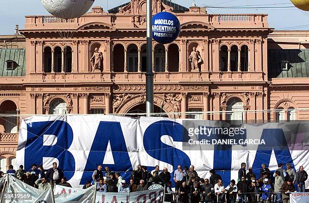 Leaders of labour unions take part in a protest with a giant banner reading "Basta" before the presidential palace 29 August 2001 in Buenos Aires....