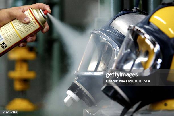 An employee tests gas masks in Sao Paulo, Brazil 21 December 2001. Un operario rocia con spray una mascara antigas para verificar su efectividad, el...