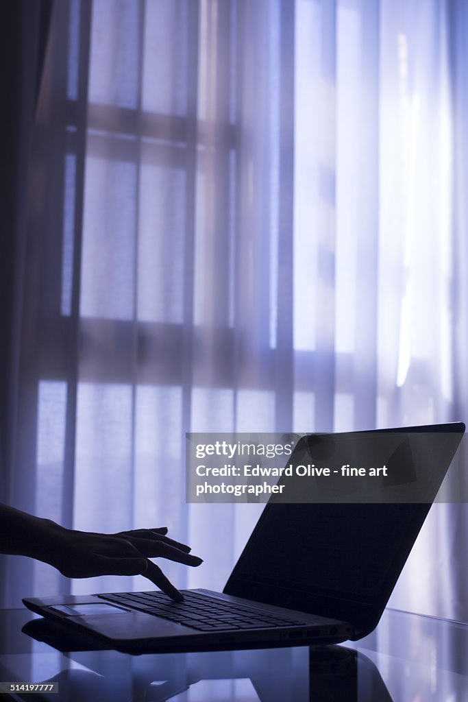 Hand typing on laptop computer on table