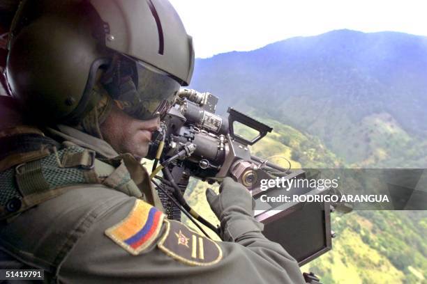 An anti-narcotics officer surveys the area in Huila, Colombia 08 March 2002. Un miembro de la Policia antinarcoticos a bordo de un helicoptero vigila...