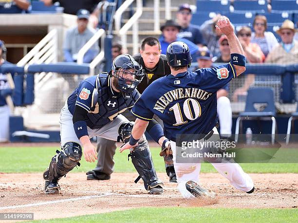 Derek Norris of the San Diego Padres tags out Kirk Nieuwenhuis of the Milwaukee Brewers at home plate during the second inning of a spring training...
