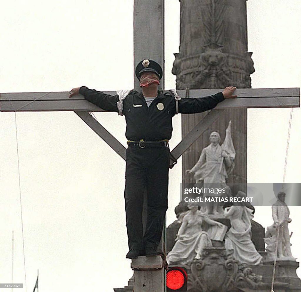 A Mexican policeman stands tied to a wooden cross