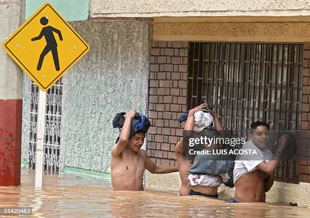 Four people walk in water up to their waist after the Tunjuenlito river overflowed 09 June 2002. Due to the torrential downpours, 2500 people lost...