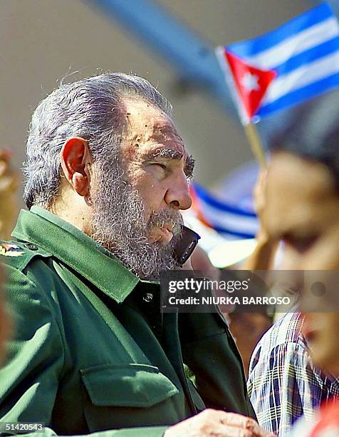 Cuban President Fidel Castro pauses to talk on a cell phone during a protest by nearly half a million Cuban women 02 June 2000, outside the US...