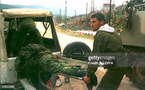 Two Israeli soldiers carry the body of an Iranian-backed Hezbollah guerrilla, killed along with two others, in clashes with the Israeli army, 25...