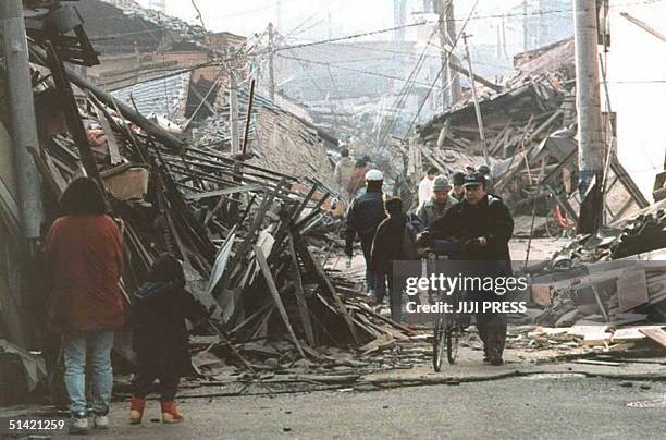 People walk down a devastated Kobe street 18 January following the earthquake that hit western Japan 17 January. The National Police Agency said over...