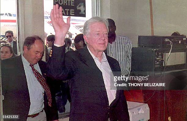Former US President Jimmy Carter waves to reporters 23 February upon his arrival at Port-au-Prince International Airport. Carter,who is heading a US...