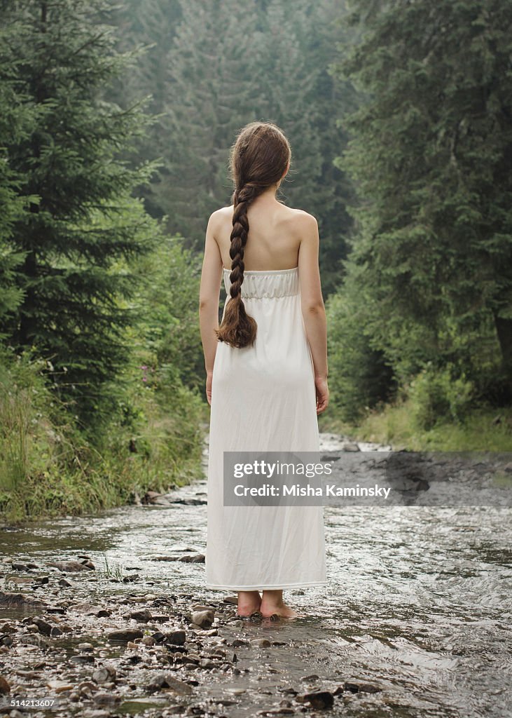 Jeune femme va pieds nus sur la rivière de montagne