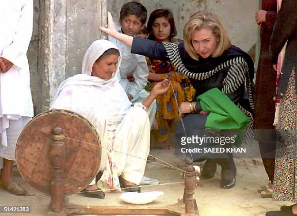 First Lady Hillary Clinton watches a local woman working on a traditional spinning wheel at Burki village near the Pakistan-India border 27 March....