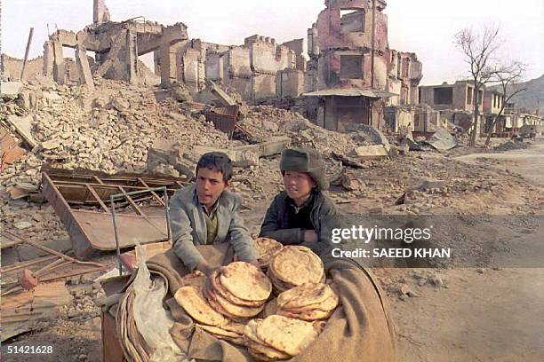 Two Afghan children sell Nan bread near the ruins of a former shopping boulevard in eastern Kabul 21 February, an area which was the site of...