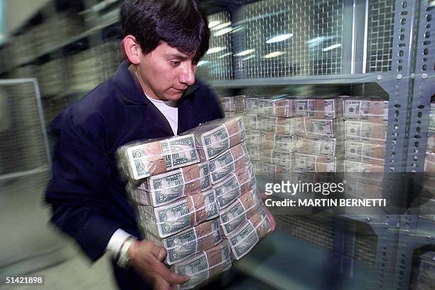 An employee of the Treasury department of Ecuador carries $5 bill bundles within the vault of the institution in Quito, Ecuador, 16 November, 2000....