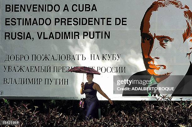 Woman passes a billboard on a Havana street welcoming Russian President Vladimir Putin 13 December 2000. Putin will be arriving in Havana later 13...