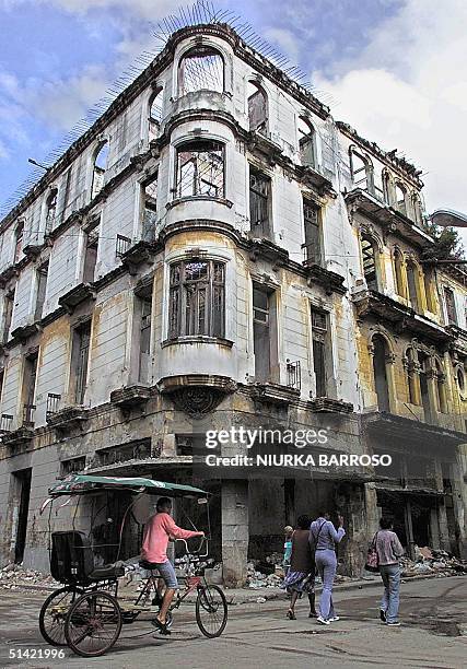 Cubans walk by a vacated building in Havana damaged by constant rains that have affected the island, 25 December 2000. Four days of constant rain...