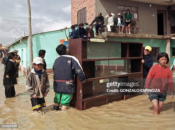 Students carry their furniture in the flooding in Viacha north of La Paz 23 January 2001. Estudiantes de un centro de estudios de la ciudad de...