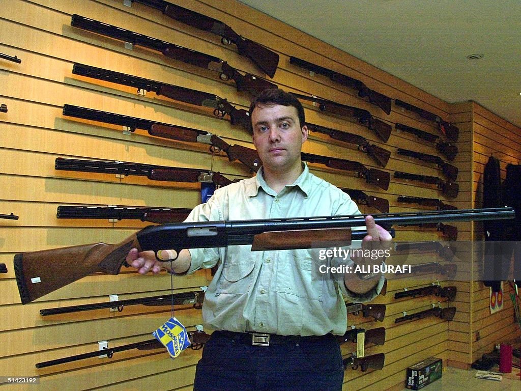 Gun shop manager Julio Caroniholds holds one of th