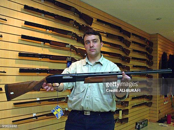 Gun shop manager Julio Caroniholds holds one of the stores more popular item, a 12 caliber rifle 24 January 2003 in Buenos Aires, Argentina. The...