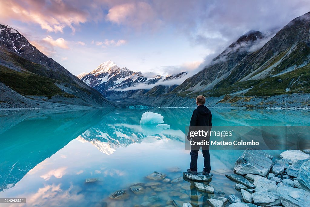 Landscape: hiker looking at Mt Cook from lake with iceberg, New Zealand