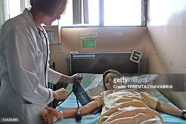 Nurse Gina Duran takes the blood pressure of boy Brandon Oconitrillo , who suffers dengue, 23 August 2002, in the unit for pacients with dengue...