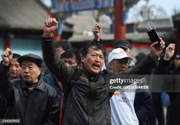 Relatives of passengers missing on Malaysia Airlines flight MH370 shout slogans outside the Lama Temple in Beijing on March 8, 2016. Relatives of...