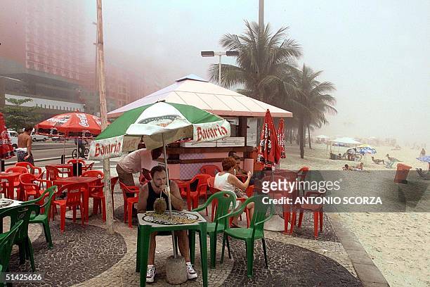 Tourists enjoy a beverage at a kiosk next to the Copacabana beach in Rio de Janerio, Brazil 09 December 1999. Turistas disfrutan de una bebida en un...