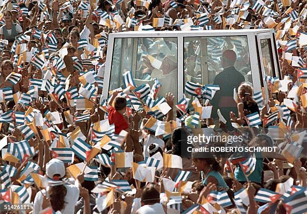 Pope John Paul II waves to a crowd of thousands of Cubans waving Cuban and Vatican flags as he arrives in the Popemobile into the Ignacio Agramonte...